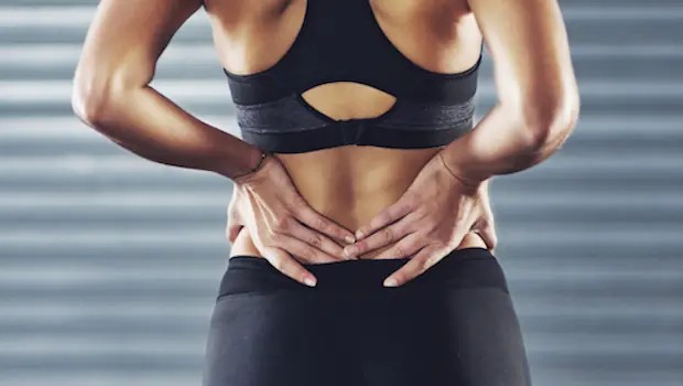 A woman holding her back while exercising.