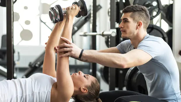 A trainer helping a woman exercise.